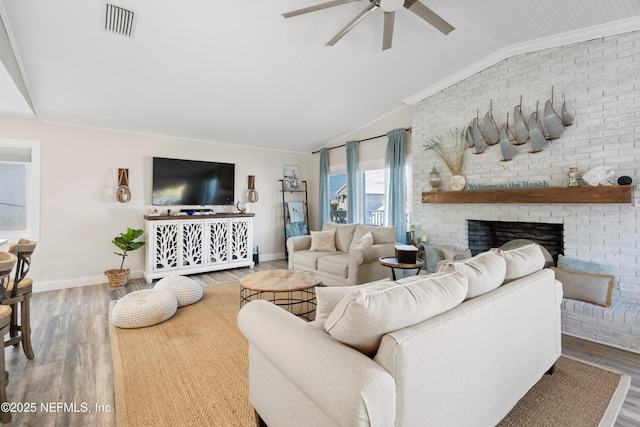 living area featuring wood finished floors, vaulted ceiling, ceiling fan, a fireplace, and baseboards