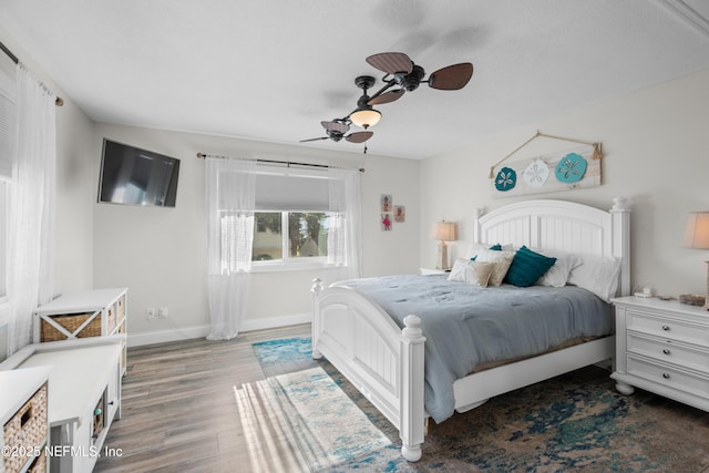 bedroom with wood finished floors, a ceiling fan, and baseboards