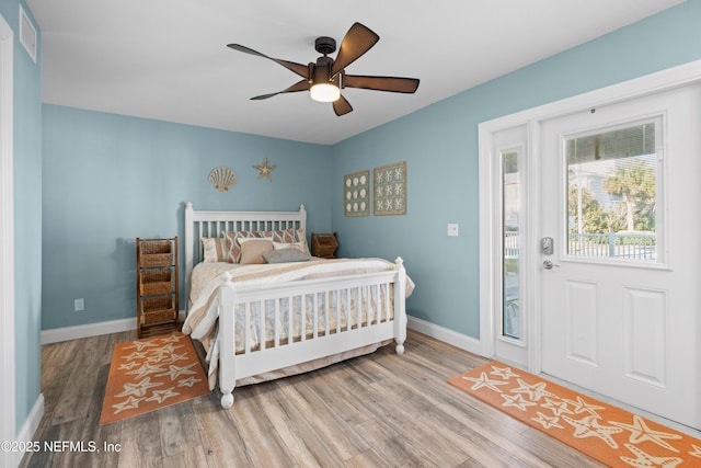 bedroom featuring a ceiling fan, visible vents, wood finished floors, and baseboards