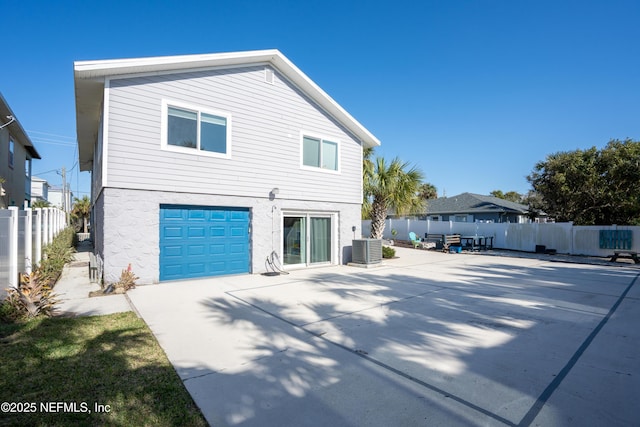 view of side of property featuring a patio, central air condition unit, a garage, driveway, and fence