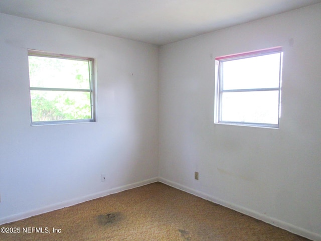 carpeted empty room featuring baseboards