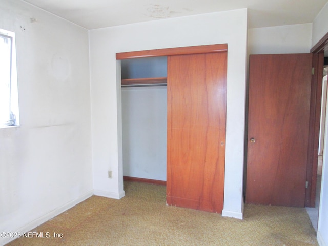 unfurnished bedroom with carpet floors, baseboards, and a closet