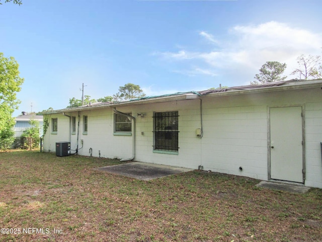 back of property featuring central AC unit, a patio area, and a yard