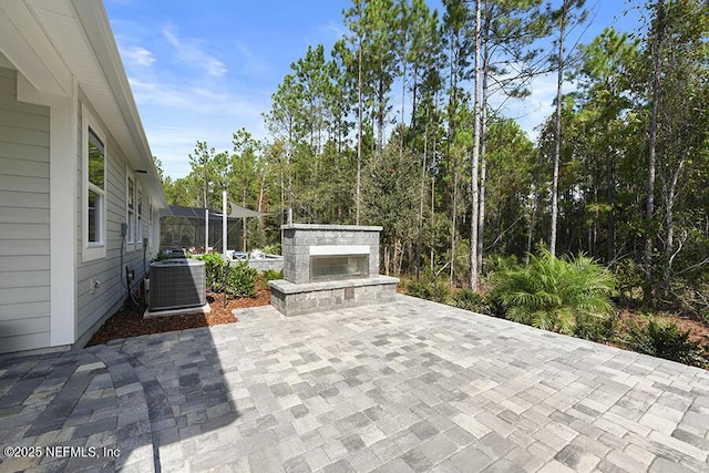 view of patio / terrace with central air condition unit and an outdoor stone fireplace
