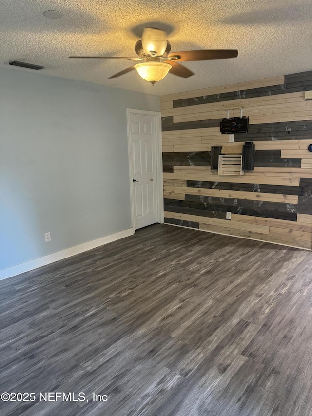 6070 Baltimore Ave, Cocoa, FL 32927 - spare room with wood walls, wood finished floors, a ceiling fan, a textured ceiling, and baseboards