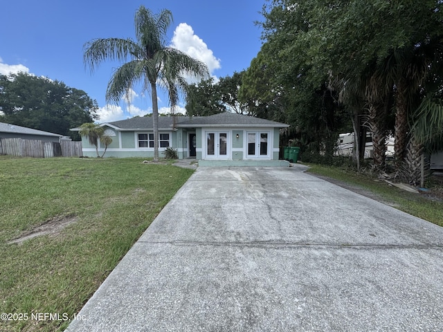 6070 Baltimore Ave, Cocoa, FL 32927 - ranch-style home with driveway, french doors, a front lawn, and stucco siding
