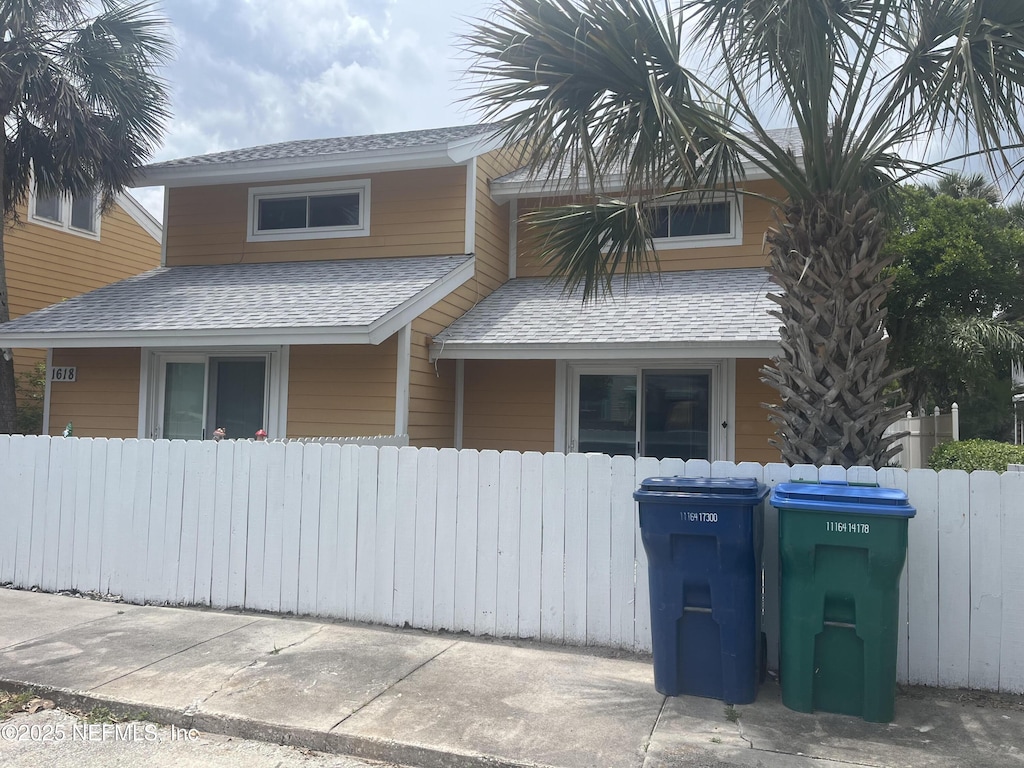 view of front of house featuring fence and roof with shingles
