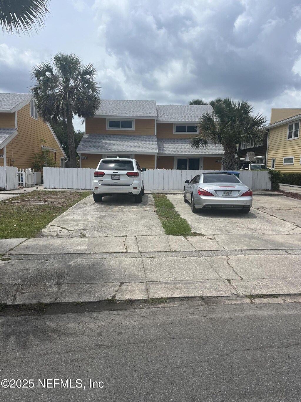view of front of property featuring driveway, fence, and roof with shingles