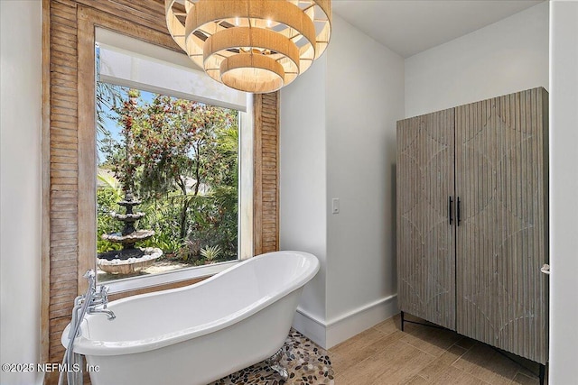 301 S Roscoe Blvd, Ponte Vedra Beach, FL 32082 - bathroom with a freestanding tub, baseboards, wood finished floors, and a notable chandelier