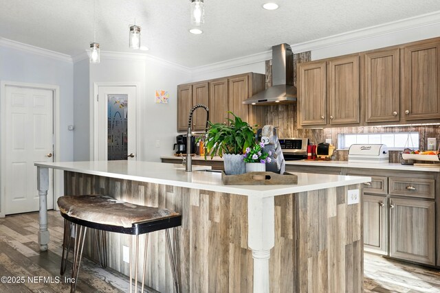 1417 Marlee Rd, Saint Johns, FL 32259 - kitchen featuring wall chimney exhaust hood, light wood-style floors, a center island with sink, light countertops, and ornamental molding
