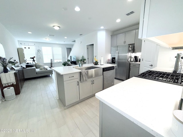 kitchen featuring light countertops, gray cabinets, a kitchen island with sink, and stainless steel appliances