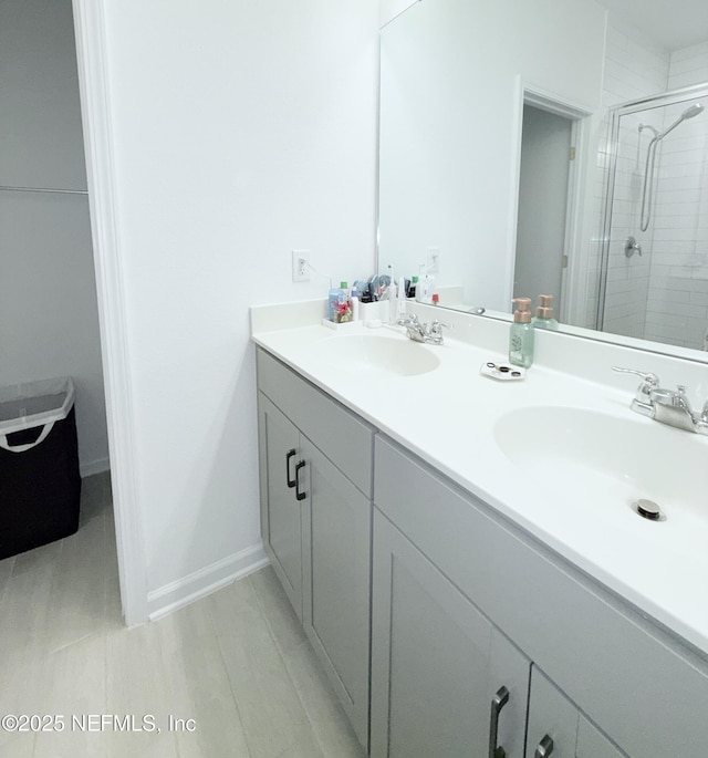 bathroom featuring a sink, a stall shower, and double vanity