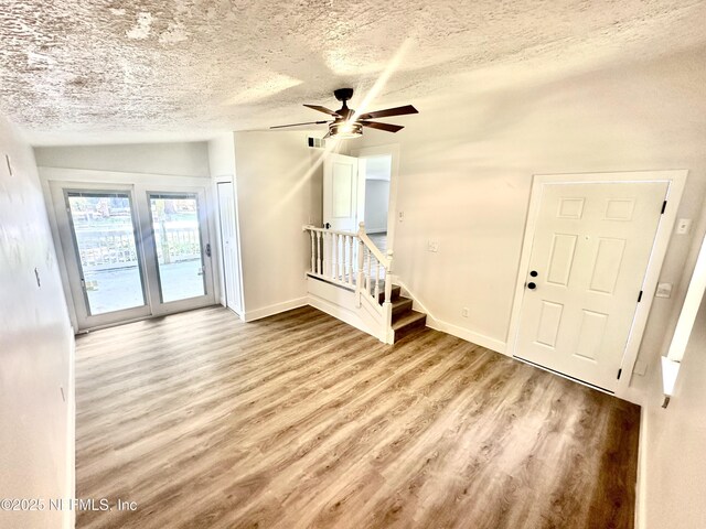 360 Varella Ave, Saint Augustine, FL 32084 - unfurnished living room featuring wood finished floors, ceiling fan, a textured ceiling, baseboards, and stairs