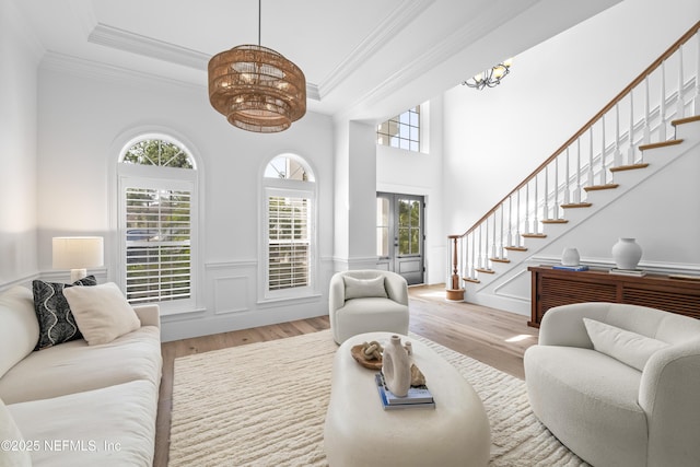 living area with an inviting chandelier, crown molding, wood finished floors, and stairway