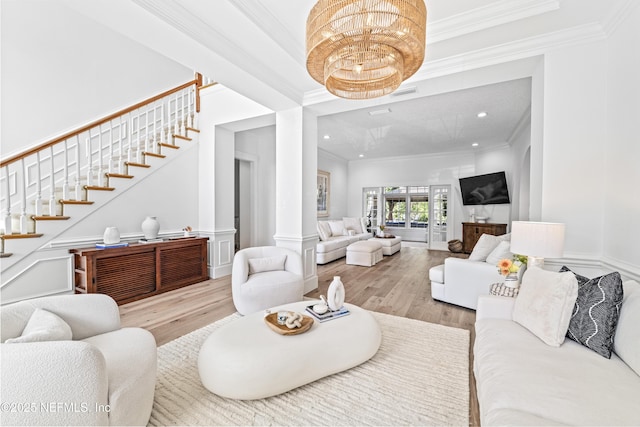 living area with stairway, crown molding, decorative columns, and wood finished floors