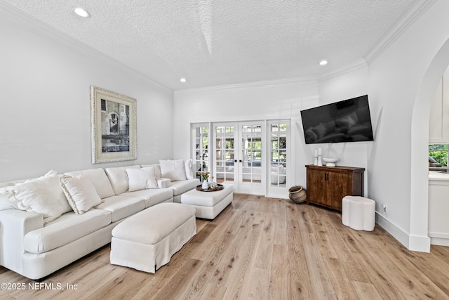 living room featuring arched walkways, a textured ceiling, french doors, and light wood-type flooring