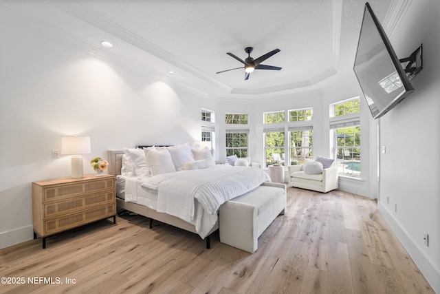 bedroom featuring baseboards, ornamental molding, a raised ceiling, and light wood finished floors