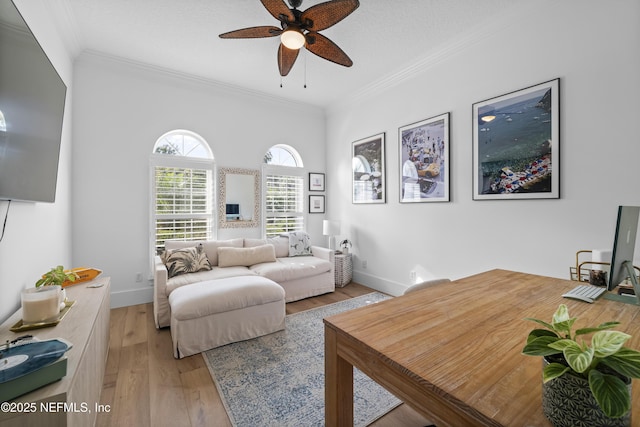 living area with a ceiling fan, baseboards, ornamental molding, and light wood finished floors