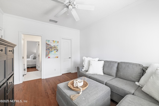 living area with visible vents, ornamental molding, dark wood finished floors, and a ceiling fan