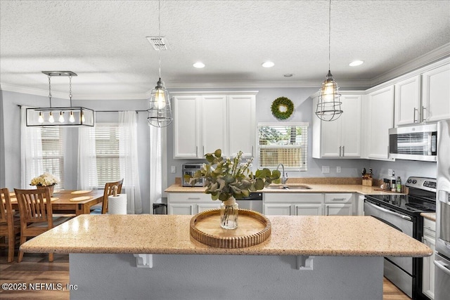 kitchen with a breakfast bar area, a sink, stainless steel appliances, crown molding, and visible vents
