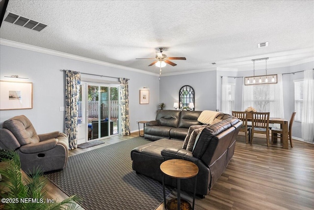 living area featuring ceiling fan, visible vents, wood finished floors, and ornamental molding