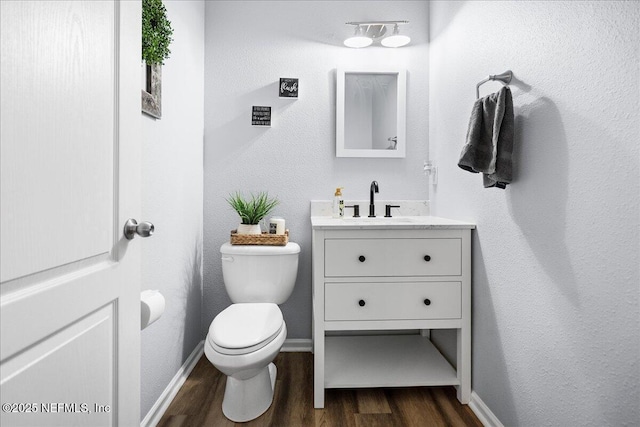 bathroom featuring toilet, baseboards, vanity, and wood finished floors