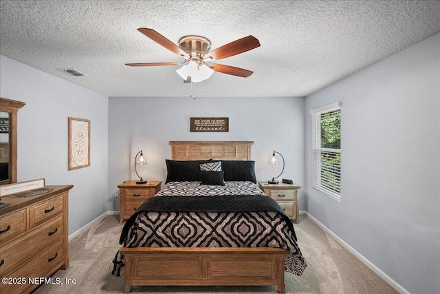 bedroom featuring a textured ceiling, baseboards, ceiling fan, visible vents, and light carpet