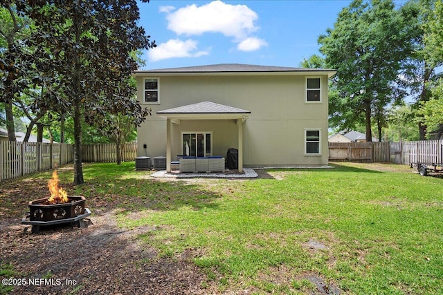 rear view of property featuring a fenced backyard, an outdoor fire pit, central air condition unit, and a lawn