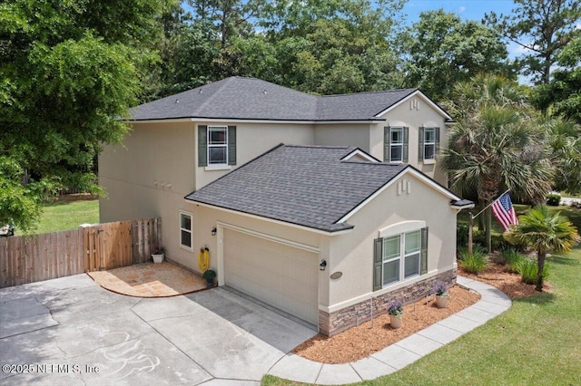 traditional-style home with an attached garage, stone siding, stucco siding, fence, and roof with shingles