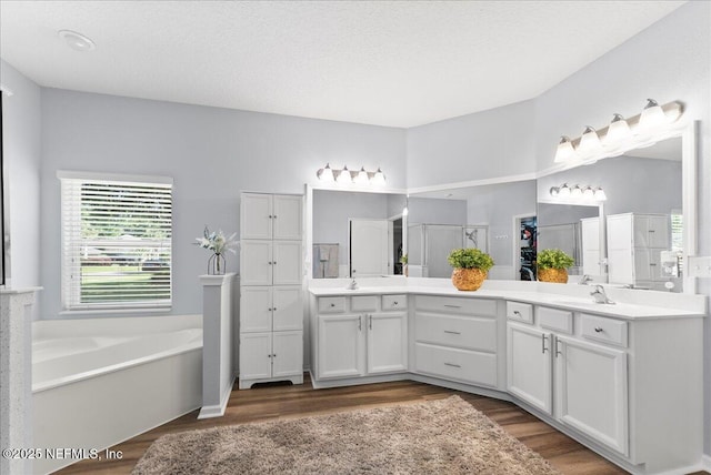 bathroom with a sink, double vanity, a shower stall, and wood finished floors