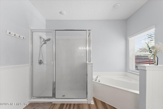 bathroom featuring a textured ceiling, a garden tub, a shower stall, and wood finished floors
