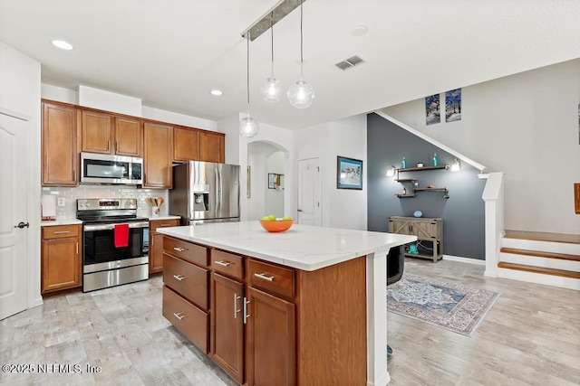 3753 Old Hickory Ln, Orange Park, FL 32065 - kitchen featuring brown cabinetry, a center island, arched walkways, appliances with stainless steel finishes, and backsplash