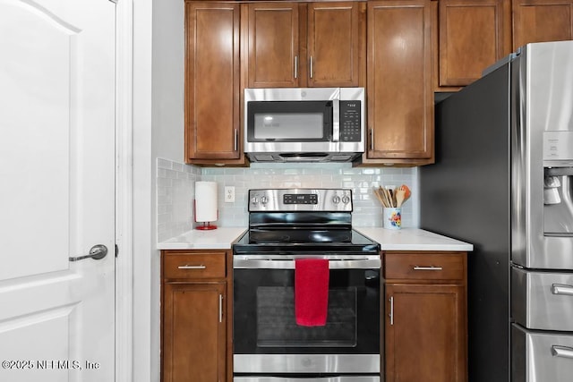 3753 Old Hickory Ln, Orange Park, FL 32065 - kitchen with light countertops, stainless steel appliances, brown cabinets, and decorative backsplash