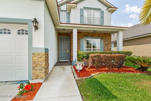 3753 Old Hickory Ln, Orange Park, FL 32065 - property entrance featuring a garage, stucco siding, a porch, and stone siding