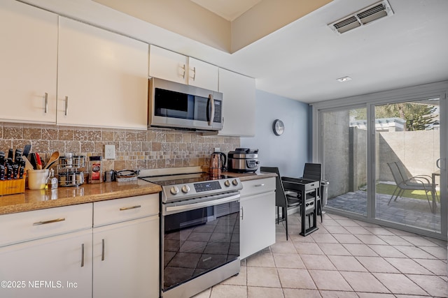 kitchen featuring stainless steel appliances, white cabinetry, decorative backsplash, light tile patterned floors, and light stone counters