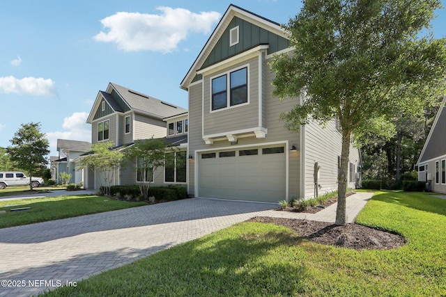 view of front of house with board and batten siding, driveway, a front lawn, and a garage