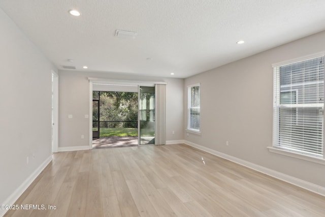 empty room featuring light wood-style floors, baseboards, recessed lighting, and a textured ceiling