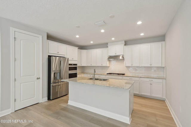 kitchen featuring light wood-style floors, a sink, decorative backsplash, and appliances with stainless steel finishes