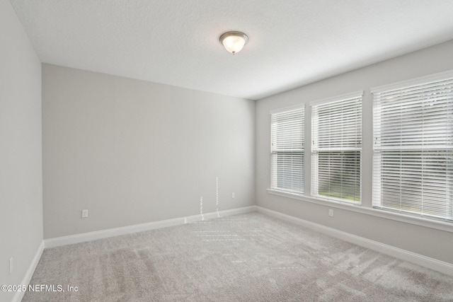 spare room featuring baseboards and carpet