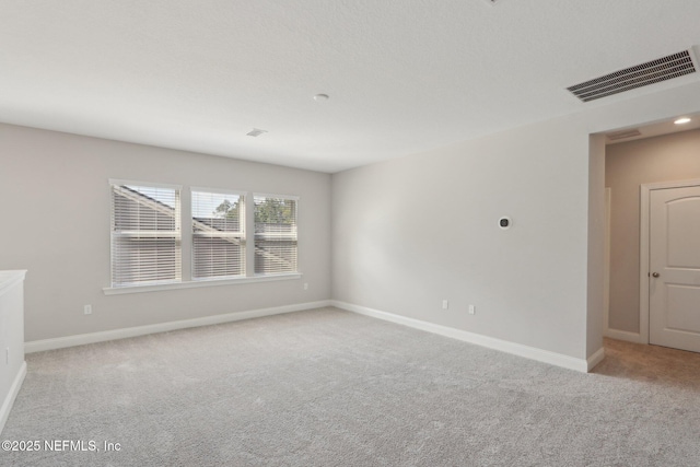 spare room with visible vents, baseboards, and light carpet