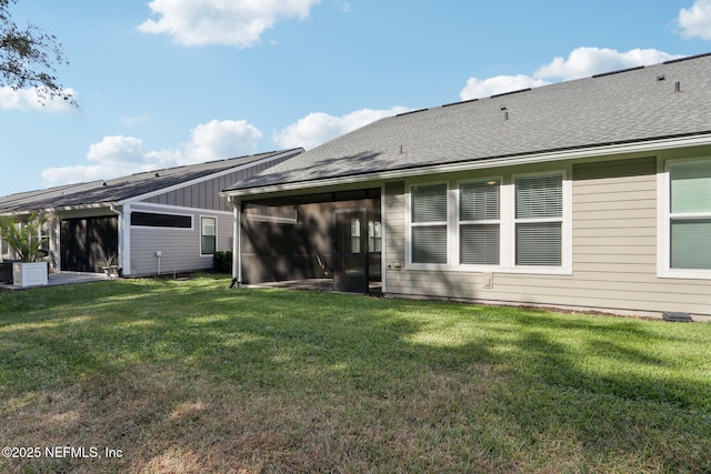 back of house featuring a yard, roof with shingles, and a sunroom