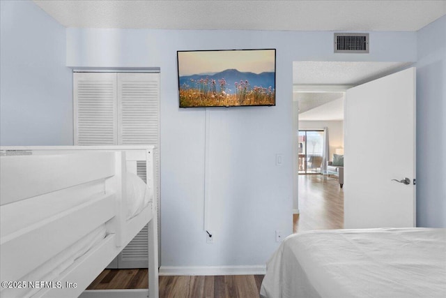 bedroom with baseboards, visible vents, and wood finished floors