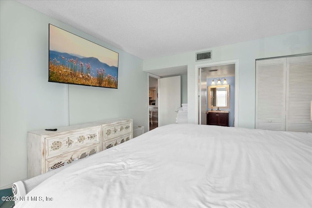 bedroom with ensuite bathroom, a closet, a textured ceiling, and visible vents