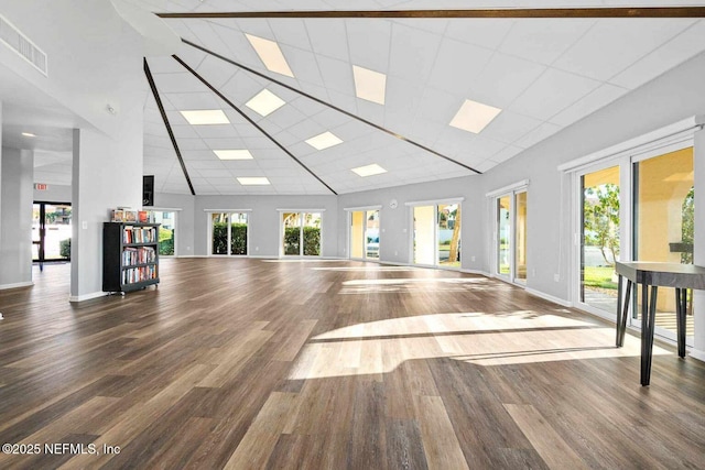 workout area featuring visible vents, a high ceiling, baseboards, and wood finished floors
