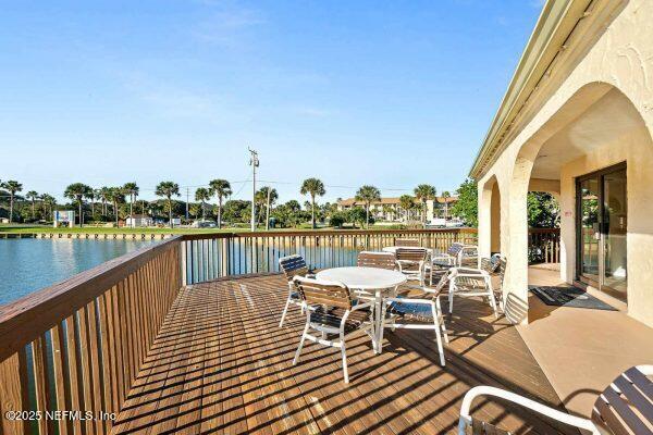 deck with outdoor dining area and a water view