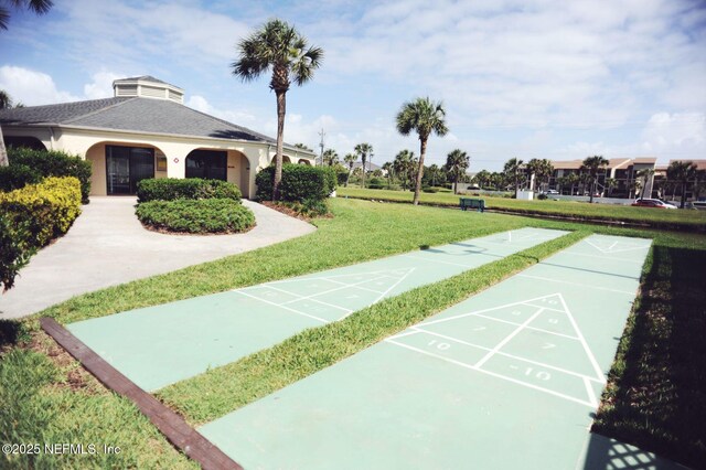 view of property's community featuring a lawn and shuffleboard