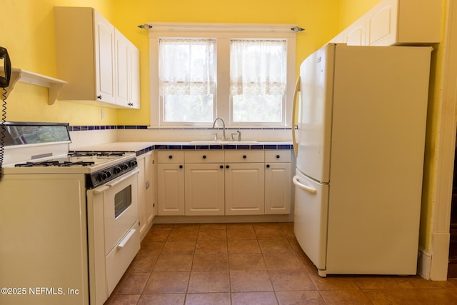 703 Emmett St, Palatka, FL 32177 - kitchen with white cabinetry, white appliances, light tile patterned flooring, and a sink
