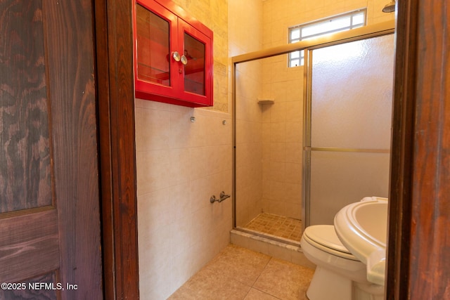 703 Emmett St, Palatka, FL 32177 - bathroom featuring tile patterned floors, toilet, a shower stall, and tile walls
