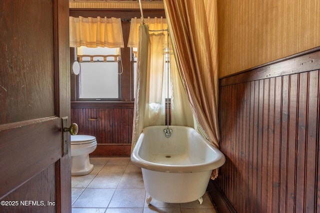 703 Emmett St, Palatka, FL 32177 - bathroom with wood walls, a freestanding bath, toilet, and tile patterned flooring