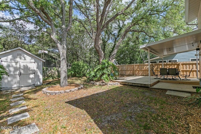 view of yard with outdoor dining area, a deck, fence private yard, an outdoor structure, and a storage unit